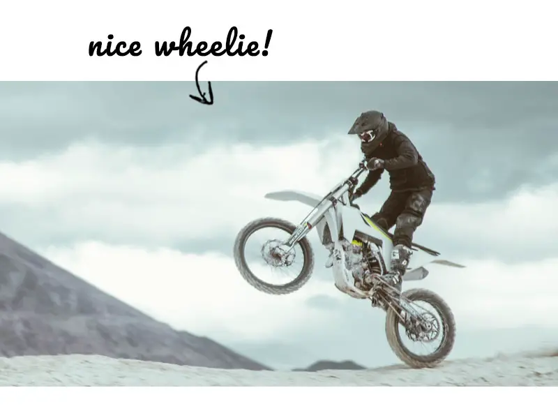 Man doing a wheelie on a dirt bike